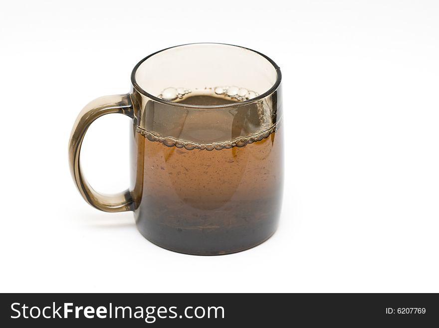 A transparent black cup with tea and tealeafs