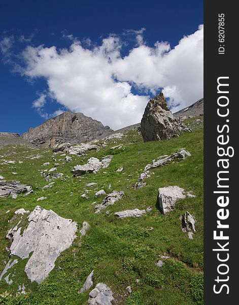 High mountain landscape with deep blue sky,  clouds and many big rocks in front, vertical. High mountain landscape with deep blue sky,  clouds and many big rocks in front, vertical