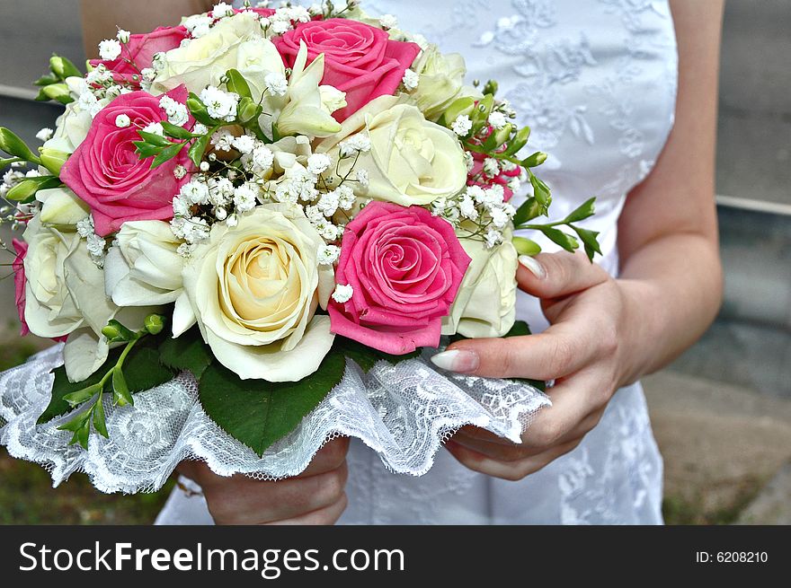 Close up of bride in white dress holding bouquet of red and pink roses,. Close up of bride in white dress holding bouquet of red and pink roses,