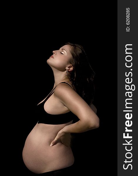 Pregnant female with a burnished gold and copper tint to her skin wearing a black bra and pants, over black background. Pregnant female with a burnished gold and copper tint to her skin wearing a black bra and pants, over black background.