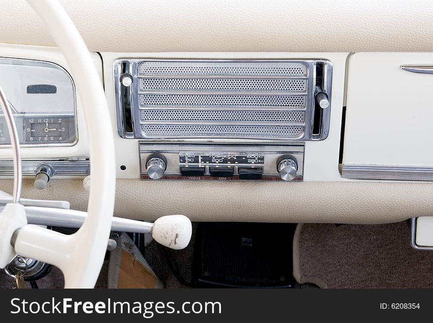 Old style steering wheel and white dashboard. It can also be seen the gear lever on th esteering column, the old stereo and the speaker. Old style steering wheel and white dashboard. It can also be seen the gear lever on th esteering column, the old stereo and the speaker.