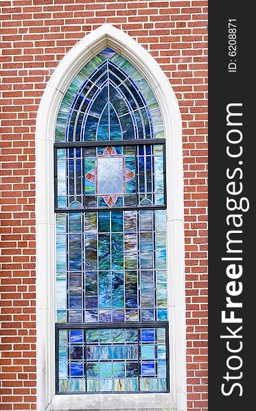 A beautiful stained glass window in a brick wall of a church