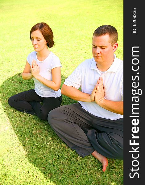 Two Caucasian Meditate On Grass