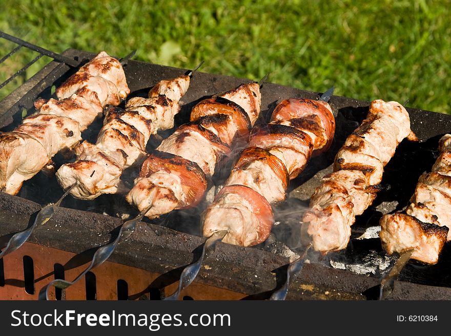 Shish kebab preparation on a brazier. Outdoor picnic. Close up.