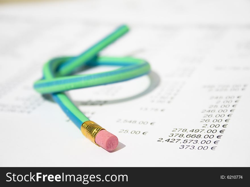 A green and blue striped rubber pencil tied in knot sitting on accounting printout. A green and blue striped rubber pencil tied in knot sitting on accounting printout