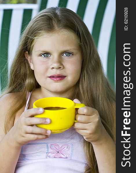 Little blond girl with yellow cup of tea in her hands. Little blond girl with yellow cup of tea in her hands