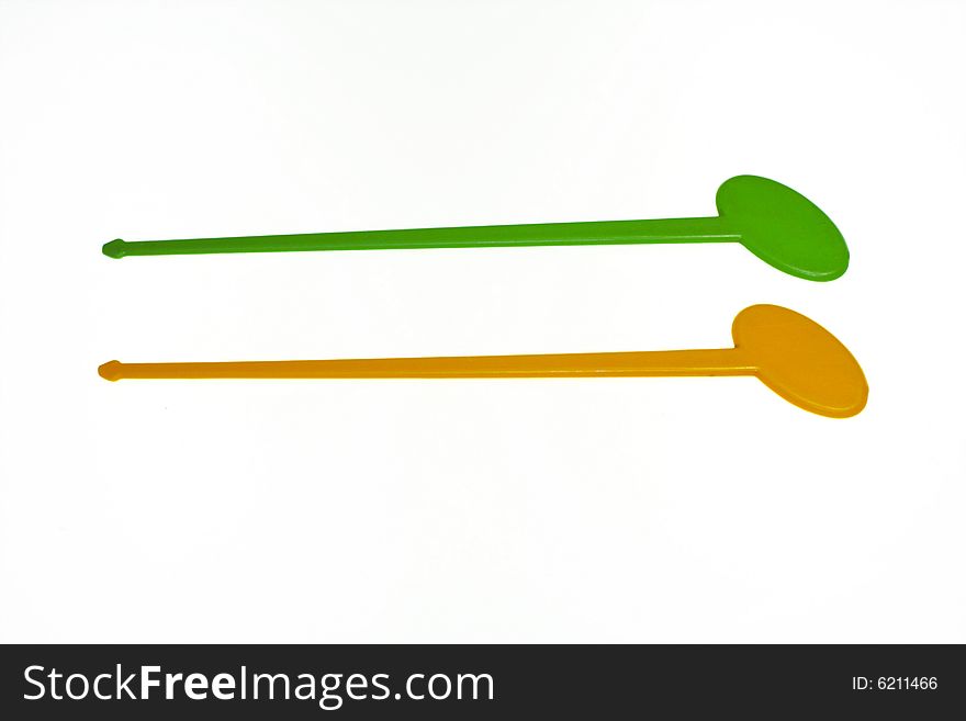 Two plastic swizzle sticks with green and orange color. Two plastic swizzle sticks with green and orange color