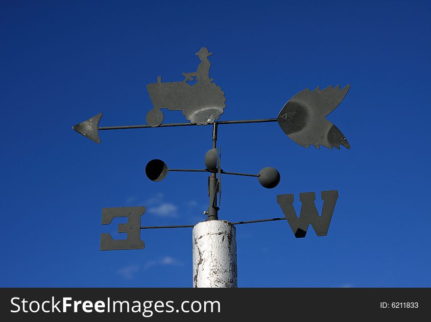 Old wind vane against clear blue sky