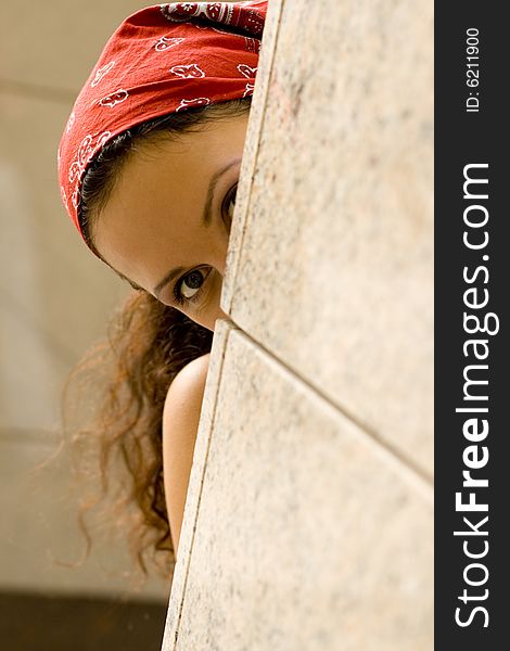 Woman in red kerchief looking behind a wal. Woman in red kerchief looking behind a wal