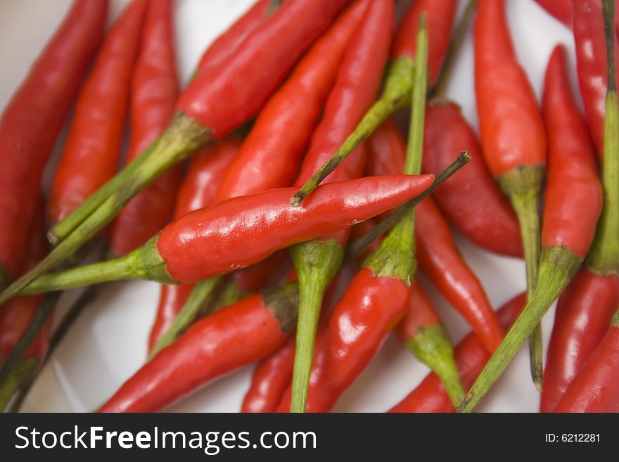 A pile of small red chili peppers arranged and isolated against a white background. A pile of small red chili peppers arranged and isolated against a white background