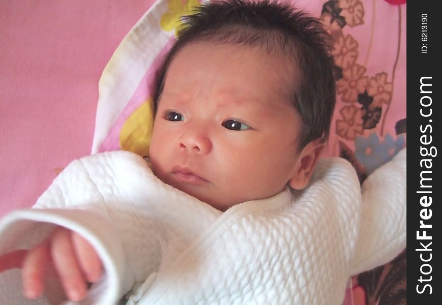 Lovely baby in white on a bed