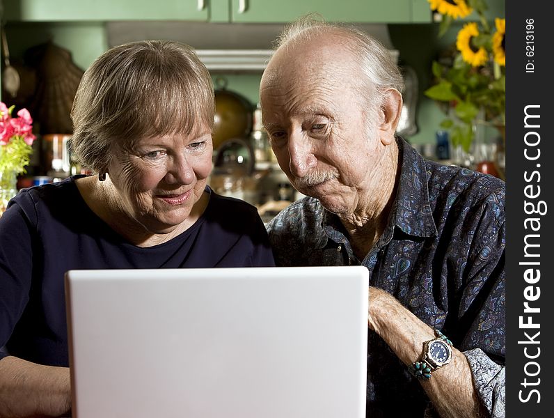 Senior Couple in their Dining Room with a Laptop Computer. Senior Couple in their Dining Room with a Laptop Computer