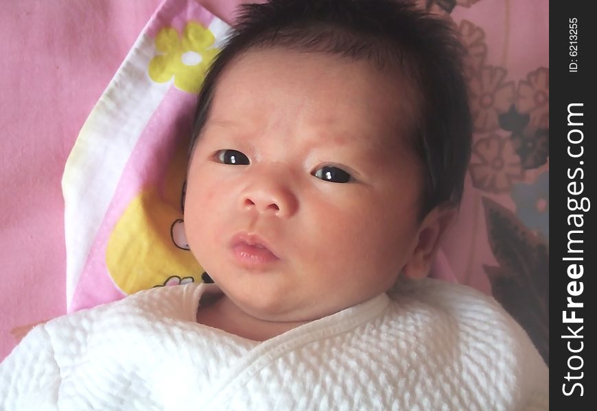 Lovely baby in white on a bed