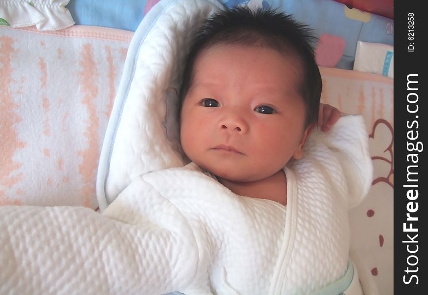 A Chinese baby is waving her hand on a bed. A Chinese baby is waving her hand on a bed