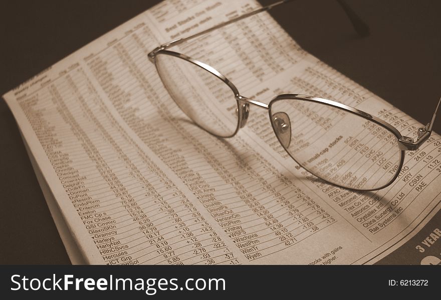 A pair of glasses lay on a newspaper opened to the stock page. A pair of glasses lay on a newspaper opened to the stock page