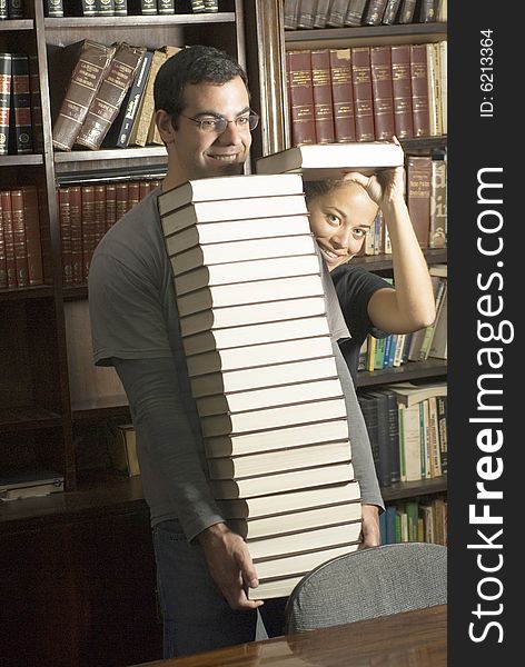 Students playing around in office stacking books. Vertically framed photo. Students playing around in office stacking books. Vertically framed photo.