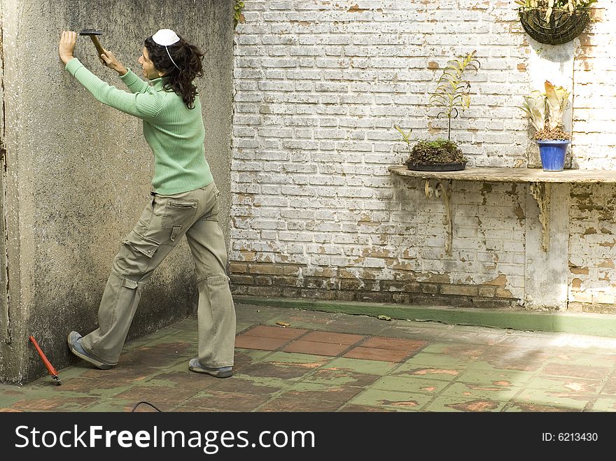 Woman hammers nail into wall. She is wearing a dust mask on her head. Horizontally framed photo. Woman hammers nail into wall. She is wearing a dust mask on her head. Horizontally framed photo.