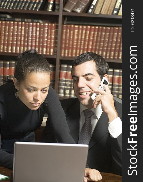 Businessman and woman looking at laptop and talking on phone. Vertically framed photo. Businessman and woman looking at laptop and talking on phone. Vertically framed photo.