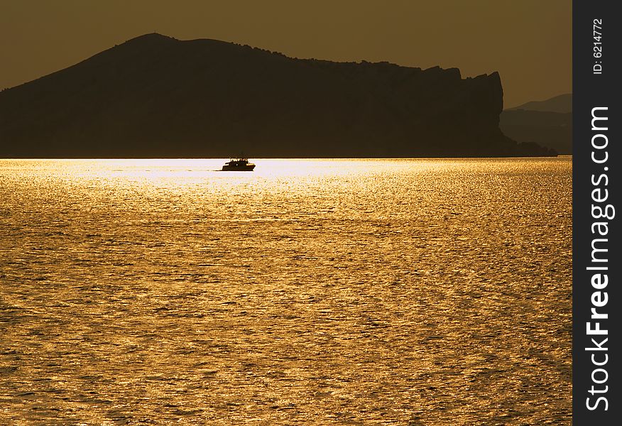 Golden sea with mount's silhouettes and ship