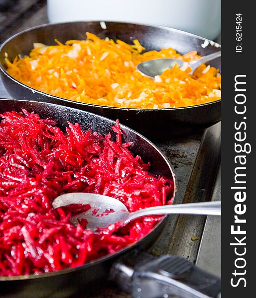 Two frying pans on a plate with a beet and a carrot