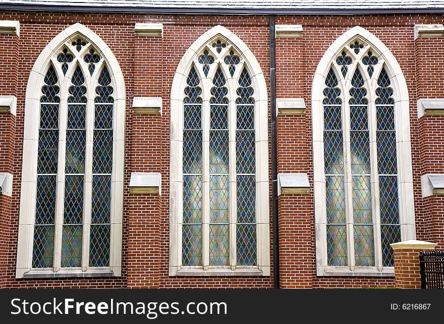 Three stained glass windows in brick wall of church