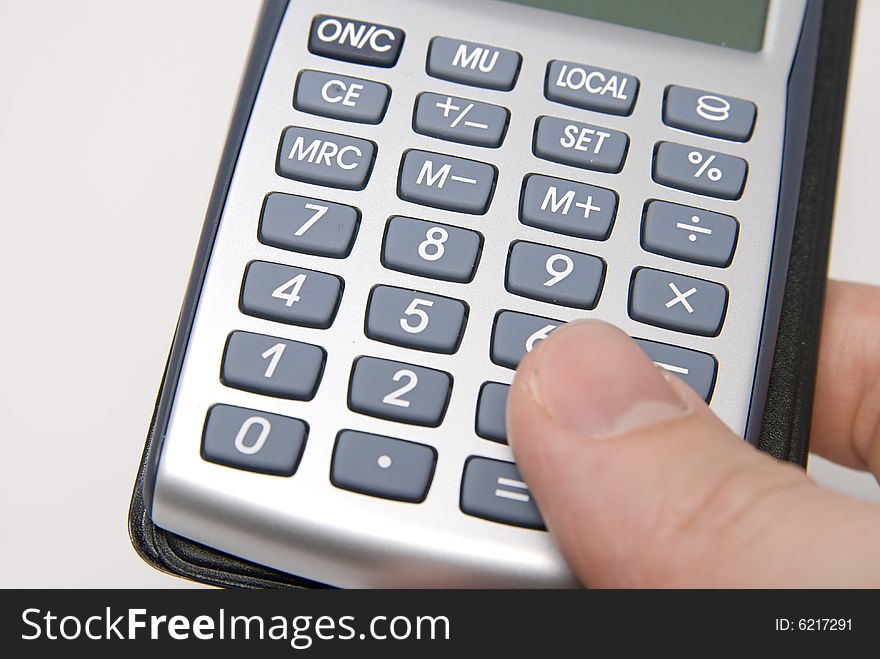 A finger pressing on a button of a calculator. A finger pressing on a button of a calculator