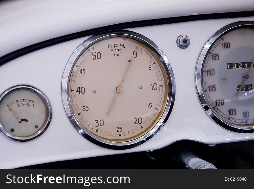 Tachometer, speedometer and fuel gauge in an old sheet steel dashboard.