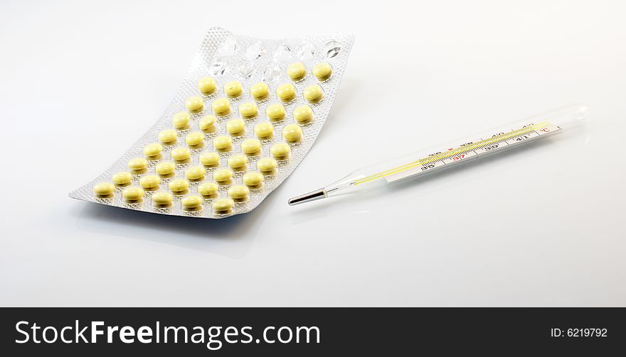 Open packaging of tablets and thermometer on a white background. Open packaging of tablets and thermometer on a white background