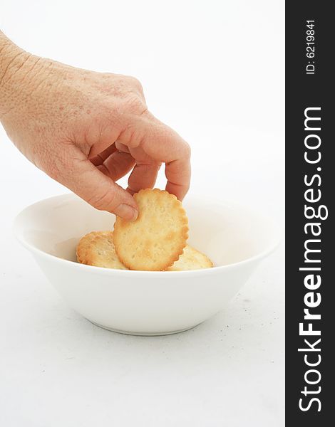 A white caucasian hand reaching into a white bowl taking a snack isolated on a white background. A white caucasian hand reaching into a white bowl taking a snack isolated on a white background.