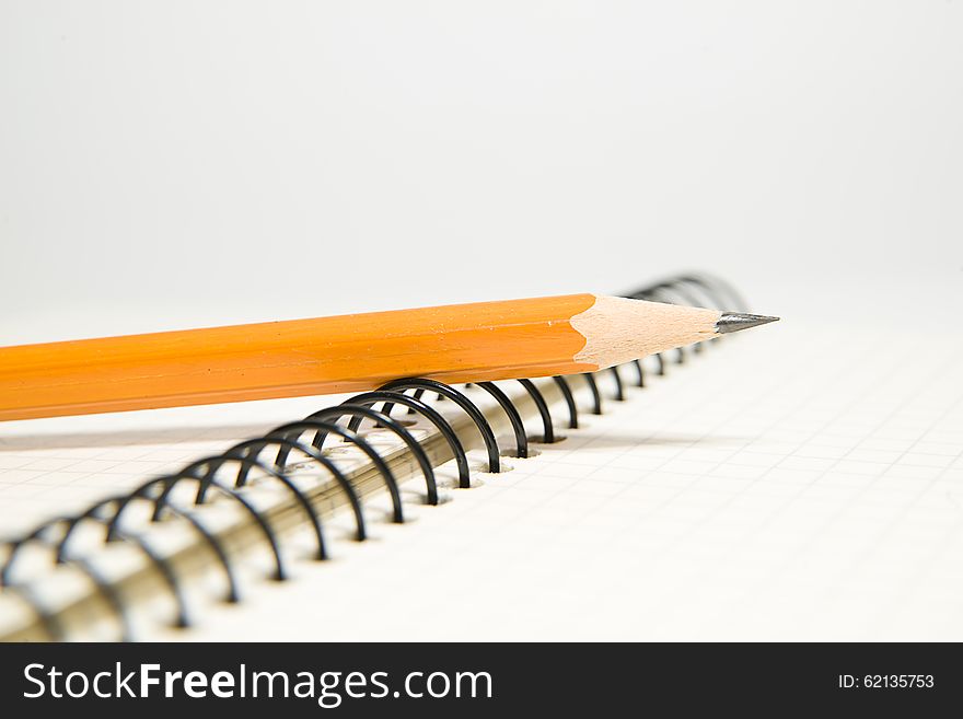 Opened notebook with a blank sheet and pencil on over white. Opened notebook with a blank sheet and pencil on over white