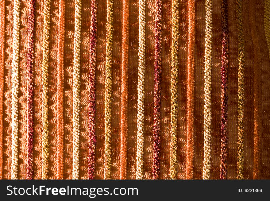 Detail of a vertical row tissue pillow, on red, orange, and purple tones. Detail of a vertical row tissue pillow, on red, orange, and purple tones