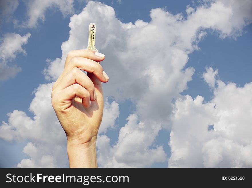 Hand holding a key in the air with the sky as a background. Hand holding a key in the air with the sky as a background