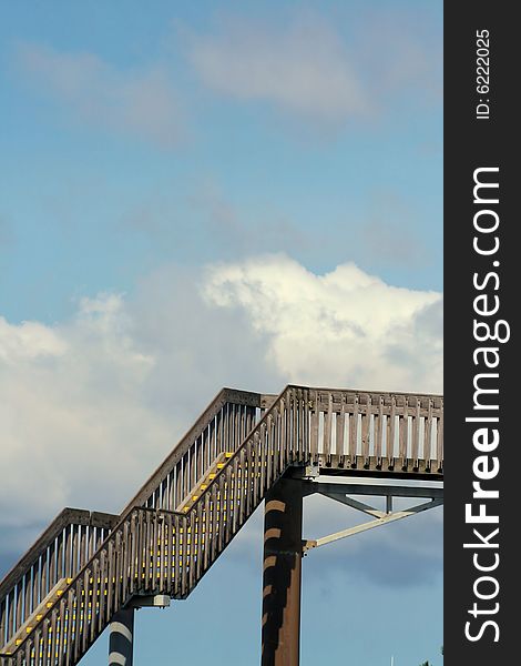 A very high wooden stairway ascending to the sky, with blue sky and clouds behind it. A very high wooden stairway ascending to the sky, with blue sky and clouds behind it