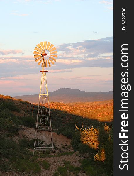 Water pumping windmill lit up at sunset in the Arizona desert. Water pumping windmill lit up at sunset in the Arizona desert