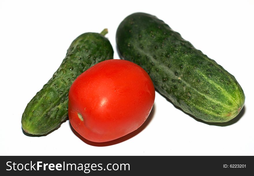 Cucumbers and a tomato on a white background. Cucumbers and a tomato on a white background