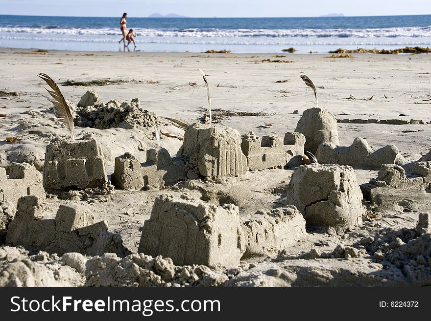 Sand castle on the ocean coast, chldren running on the background