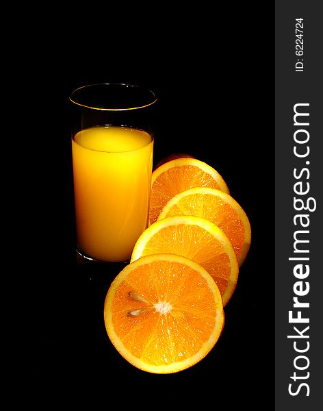 Glass of juice, oranges on black backgound. Glass of juice, oranges on black backgound
