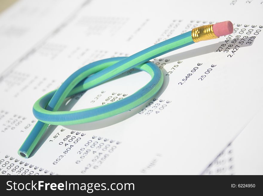 A green and blue striped rubber pencil tied in knot sitting on accounting printout. A green and blue striped rubber pencil tied in knot sitting on accounting printout