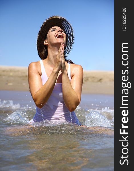 Woman praying in ocean with waves and hat