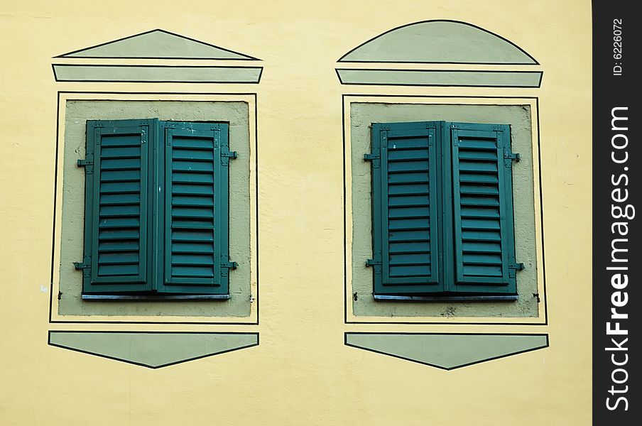 Two turquoise windows with closed shutters