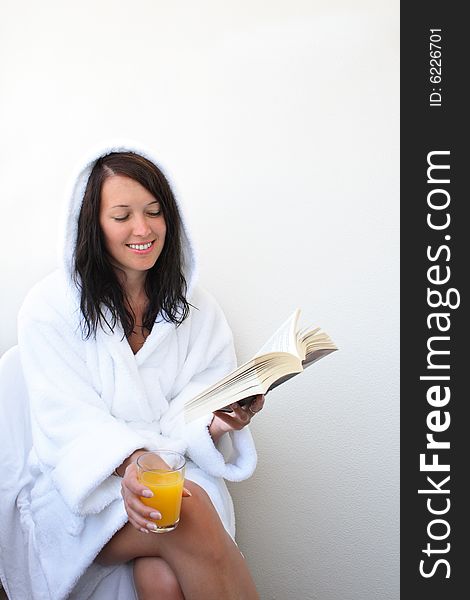Young smiling woman with orange juice reads book. Young smiling woman with orange juice reads book