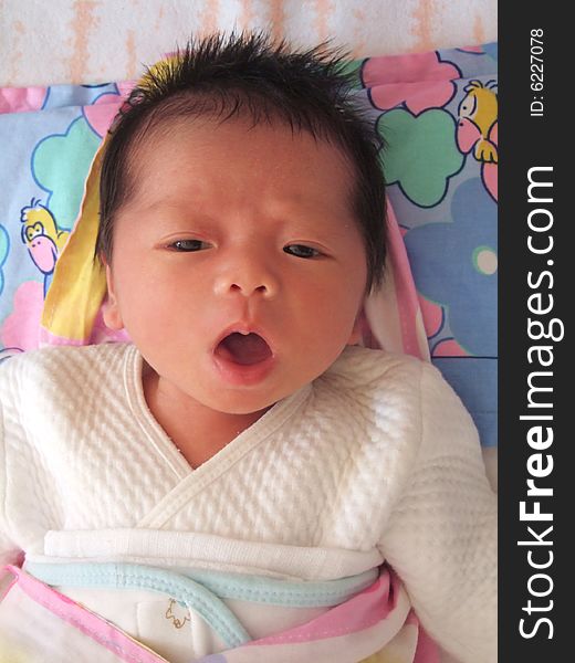 A Chinese baby on a bed, opening her mouth. A Chinese baby on a bed, opening her mouth