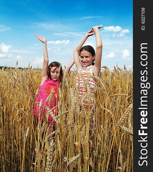 Happy girls on a field of wheat.