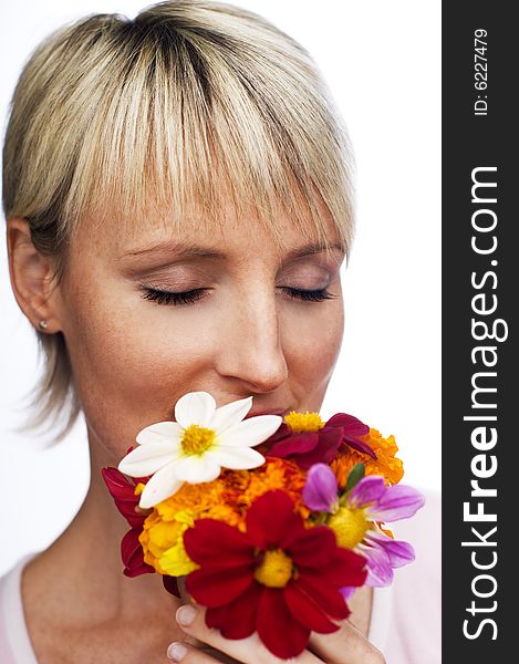 Young blond woman smelling flowers close up