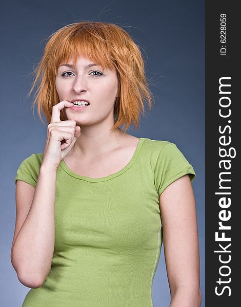 Portrait of the red-haired girl in a green T-shirt against a dark background