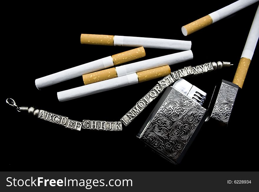 Cigarettes, a lighter and a bracelet on a black background