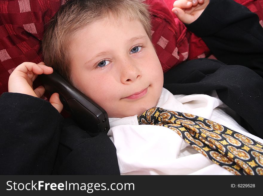 A young boy with an phone and a tie. A young boy with an phone and a tie