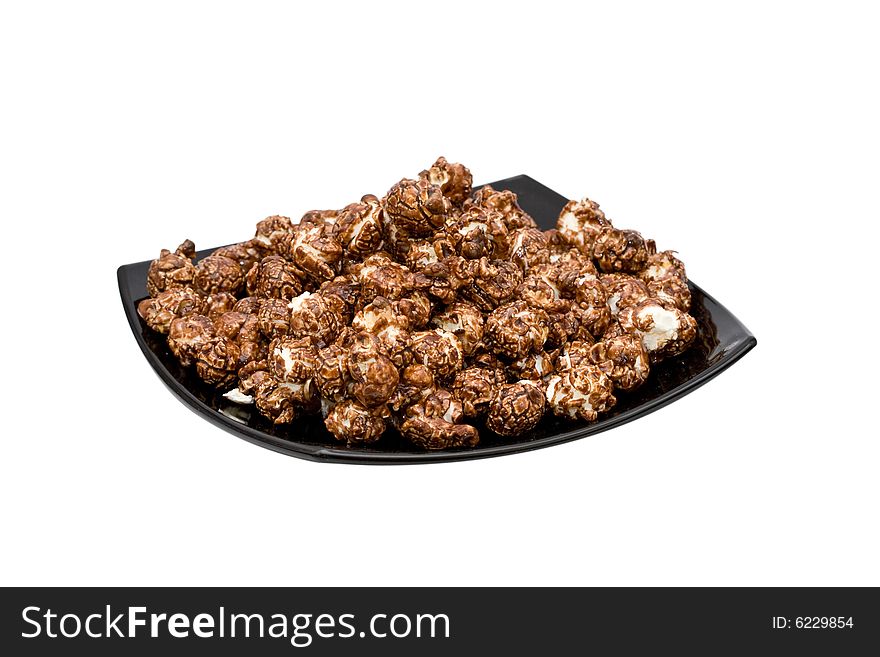 Chocolate popcorn on the black plate isolated on white