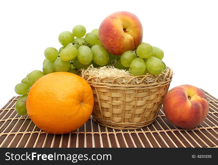Fruit in a yellow basket on a striped brown napkin on a white background