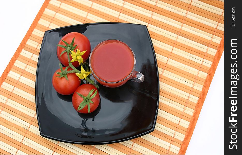On a striped orange napkin the black plate with red tomatoes